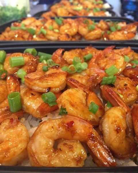 Glazed shrimp garnished with chopped green onions in a close-up serving tray