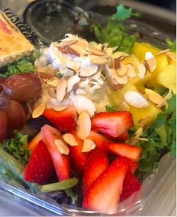 Fruit salad with strawberries, grapes, pineapple, and sliced almonds in a clear bowl