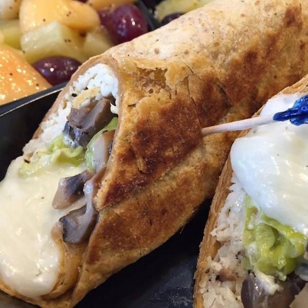 Cheesy burrito halves on a plate with grapes and a side of sour cream and guacamole