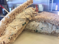 Two halves of a white bread sandwich on a plate, with visible creamy filling inside.