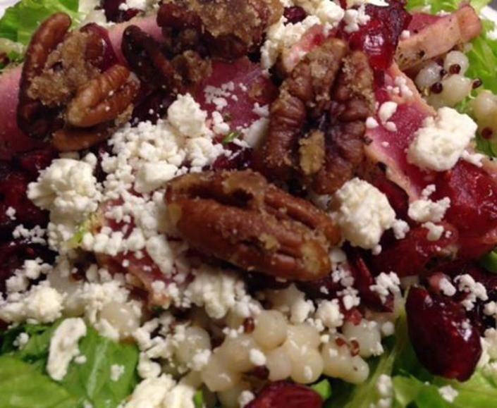 Salad with greens, beets, crumbled cheese, and walnut halves topped with creamy dressing