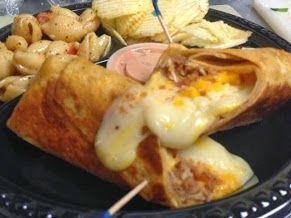 Fried wrap stuffed with melted cheese on a plate with potato chips and dipping sauce