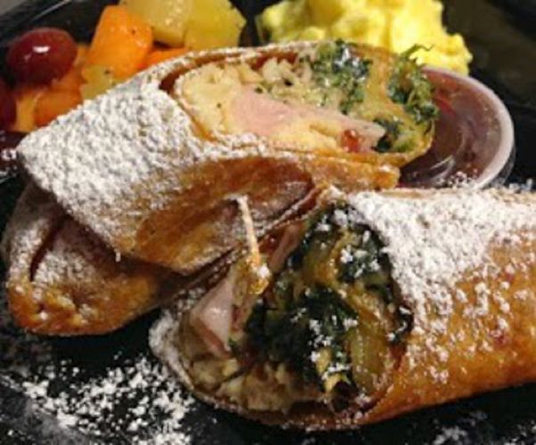 Powdered sugar-dusted pastry rolls with fruit filling on a plate