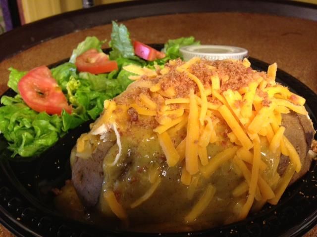 Loaded baked potato topped with shredded cheddar and bacon, served with a side salad and ranch dressing.