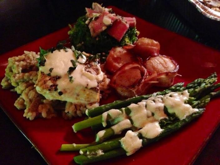 Plated gourmet meal with asparagus, potato salad, and sliced meat on a red plate