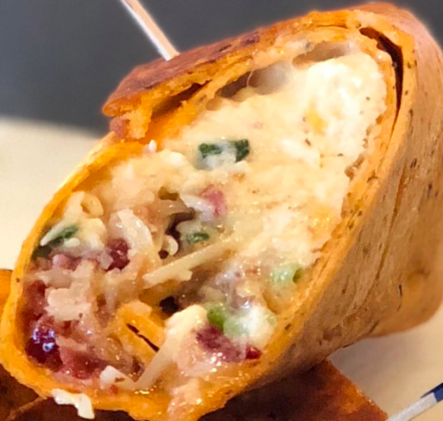 Close-up of a crispy wrap filled with melted cheese, beans, and vegetables