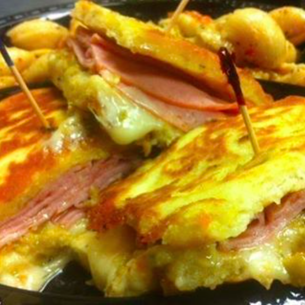 Close-up of toasted sandwich halves with melted cheese, ham, and sauce on a plate