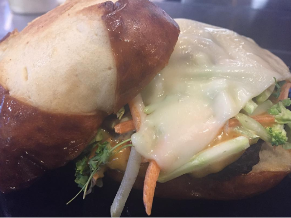 Sandwich with melted cheese, lettuce, and vegetables on a brown bun
