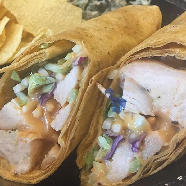 Close-up of two crispy chicken tacos with shredded lettuce and purple cabbage on a plate