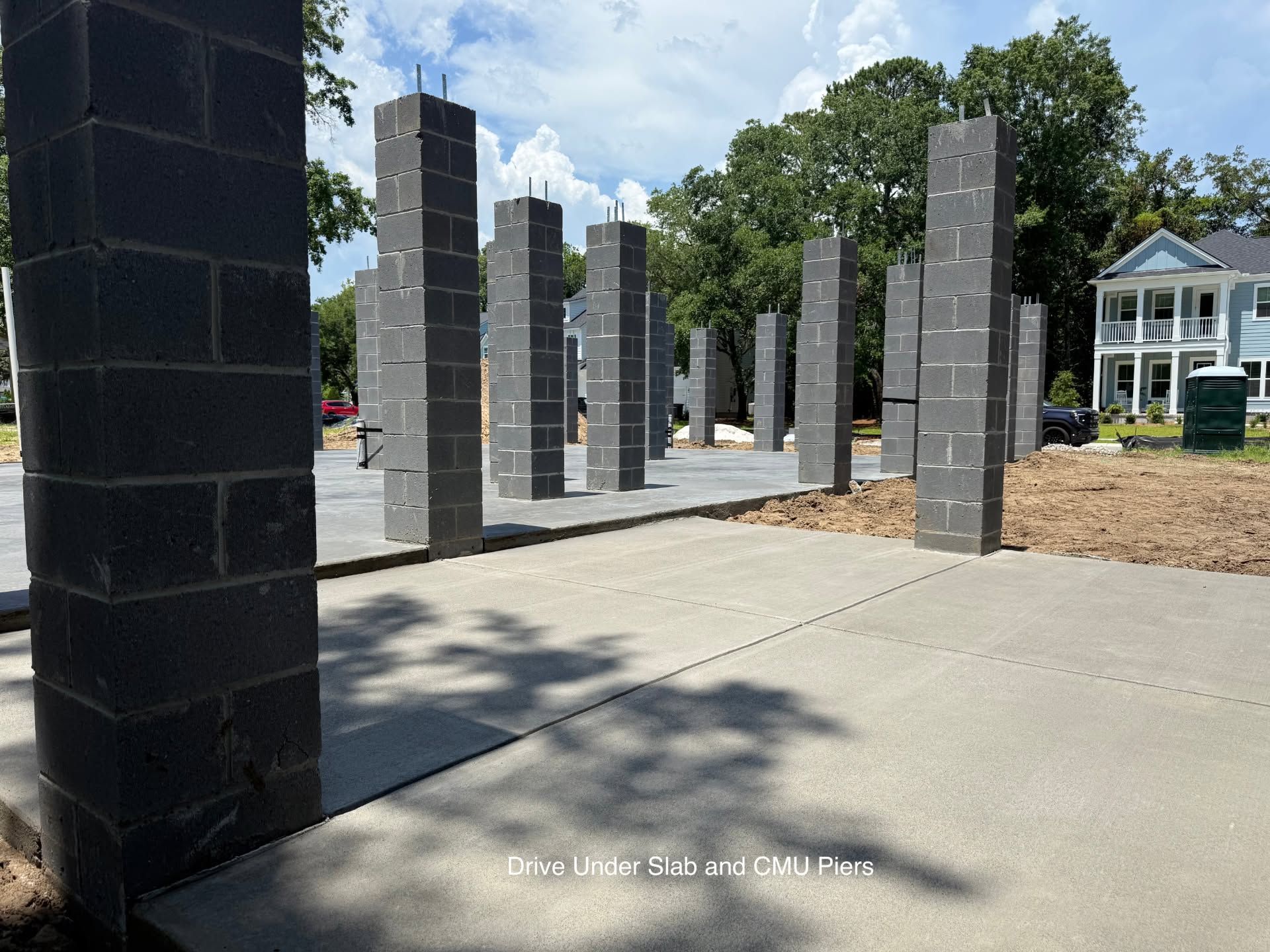 Outdoor walkway with tall gray stone columns, concrete ground, and trees in the background