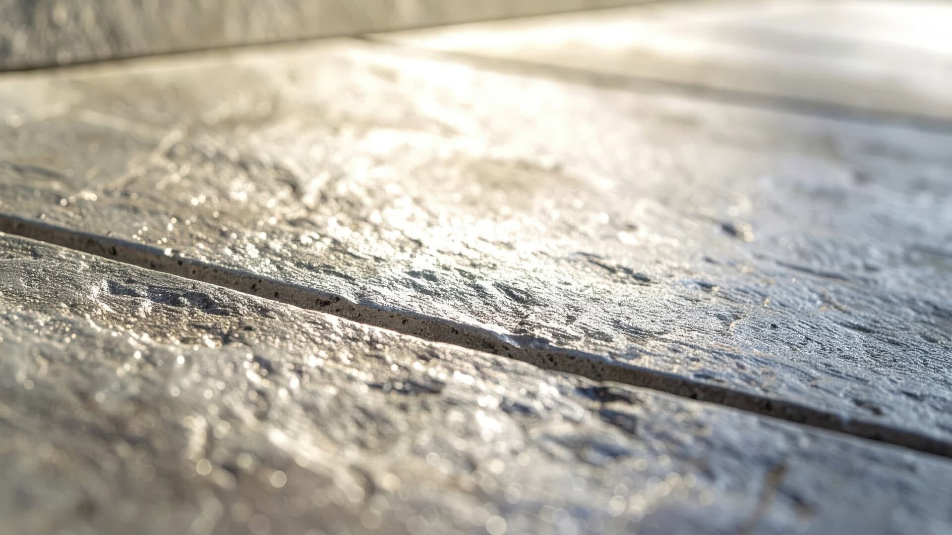 Close-up of weathered wooden boards with a shallow groove and sunlight reflecting across the surface