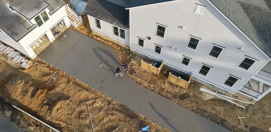 Aerial view of a narrow road beside white buildings and a dirt embankment.