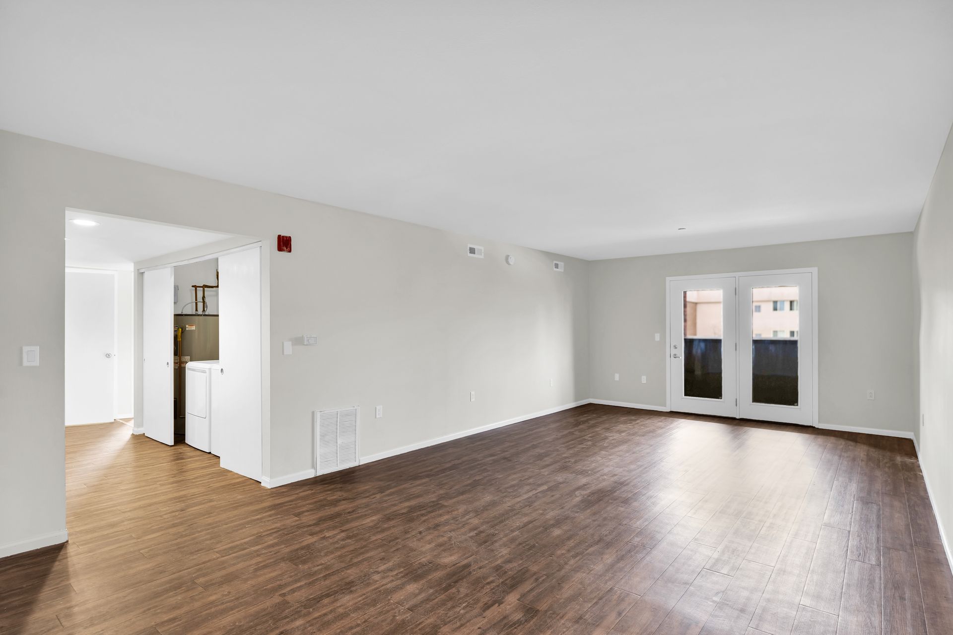 An empty living room with hardwood floors and white walls.