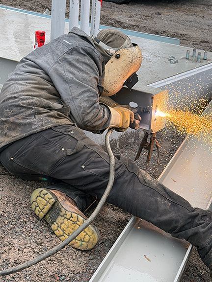 Welder working on steel I-beam with sparks flying