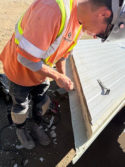 Skilled trade worker cuts down insulated metal panel for fitting.