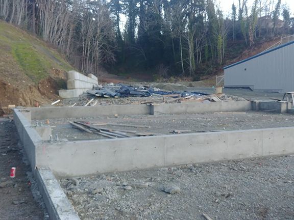 A construction site with a lot of dirt and trees in the background.
