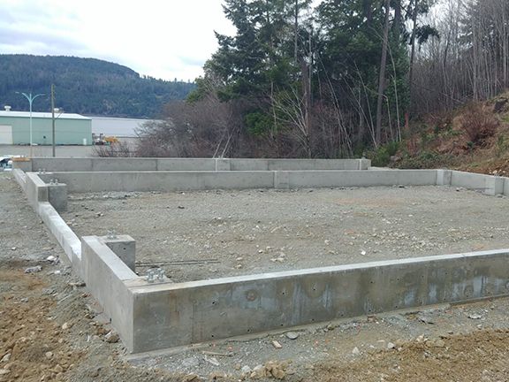 A concrete foundation is being built in a dirt field