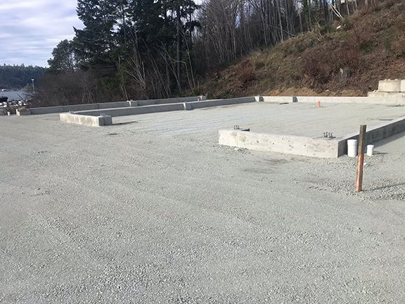A concrete foundation is being built on a hillside with trees in the background.