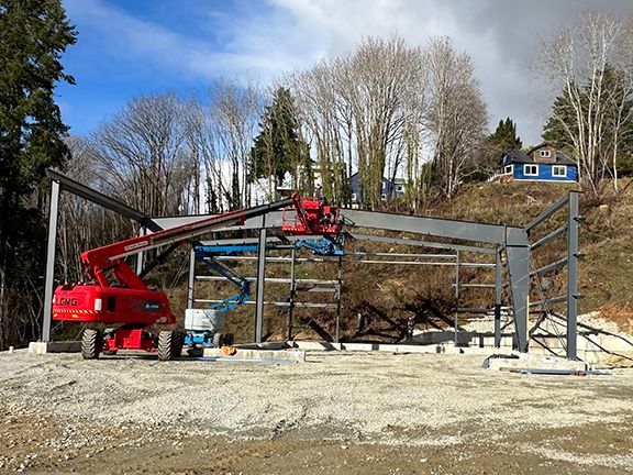 A red crane is sitting in front of a building under construction.