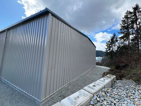 A large metal building is sitting next to a pile of rocks.
