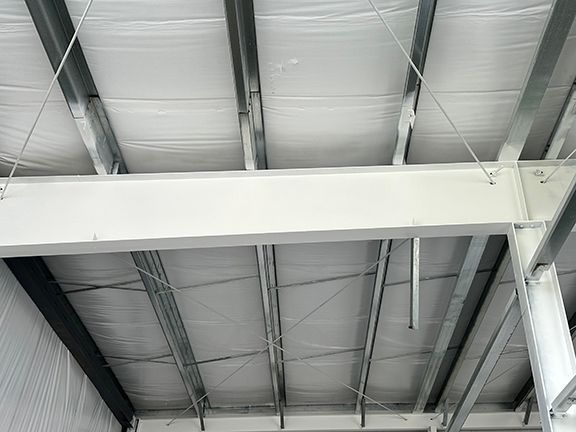 The ceiling of a building with a white beam hanging from it.