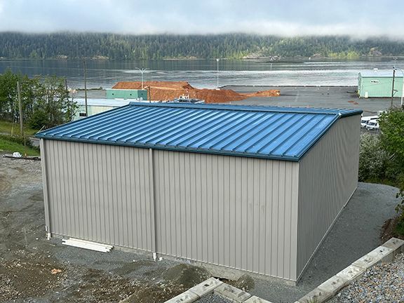 A building with a blue roof is sitting on top of a dirt hill.