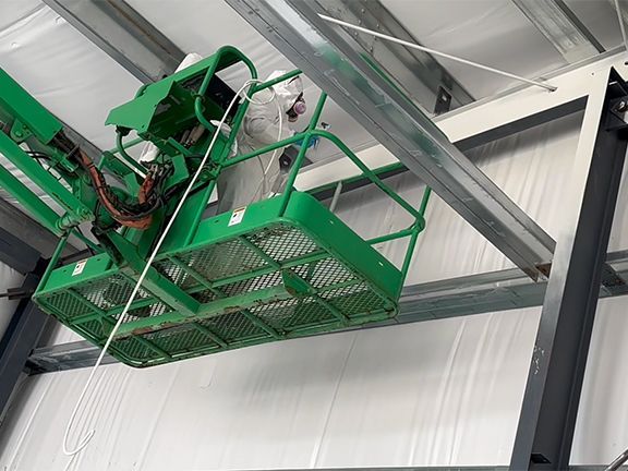 A green crane is hanging from the ceiling of a building.