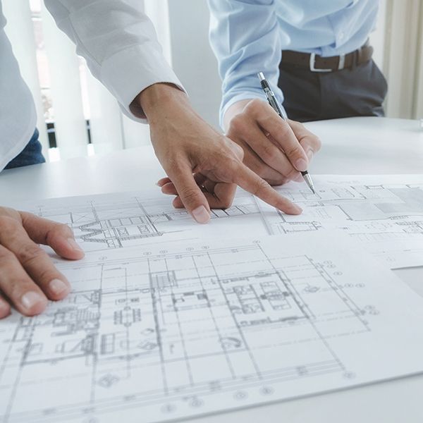Two men are looking at a drawing of a house on a table.