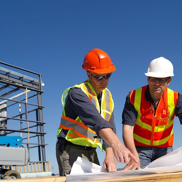 Two construction workers are looking at a blueprint