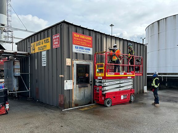 A man is standing on a scissor lift in front of a building.