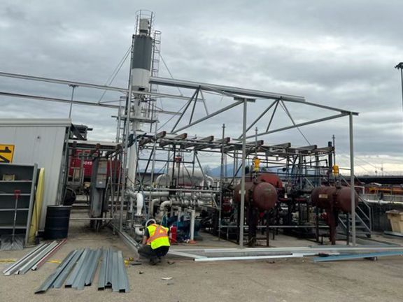 A man in a yellow vest is working on a metal structure