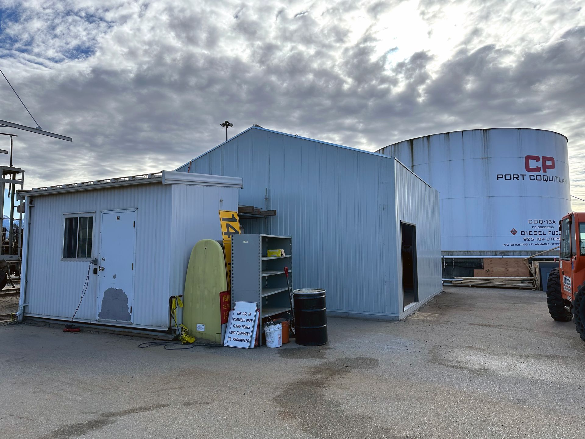 A small white building with a large white tank in the background.