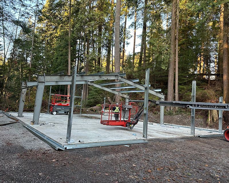 A large metal structure is being built in the middle of a forest.