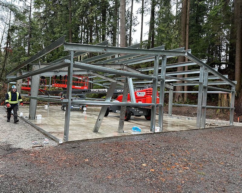 A man is standing in front of a metal structure under construction.