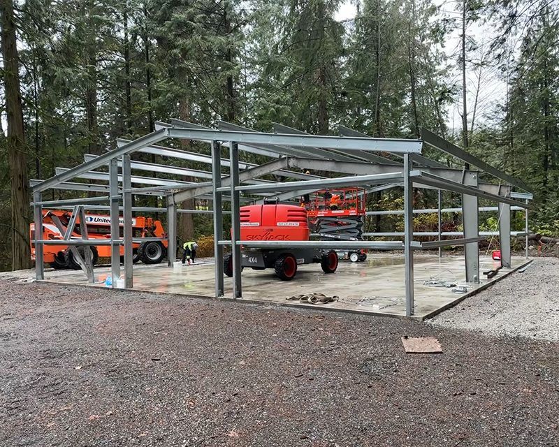 A large metal structure is being built in the woods.