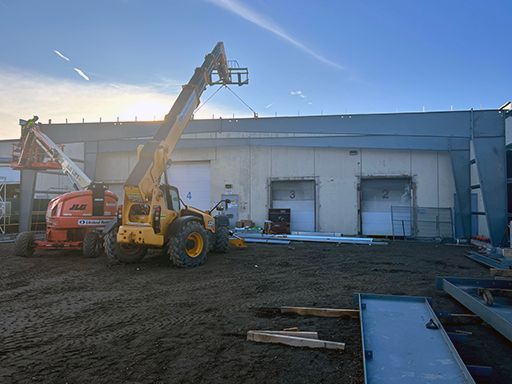 A yellow forklift is parked in front of a building.