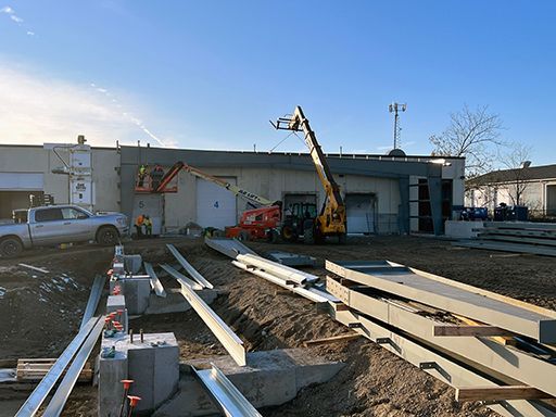 A construction site with a truck and a crane in front of a building.