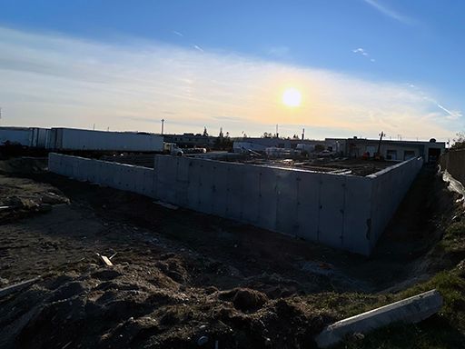 A large concrete wall is surrounding a construction site.