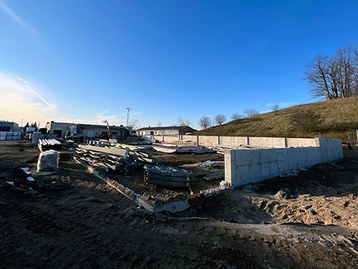 A large concrete wall is being built in a dirt field.