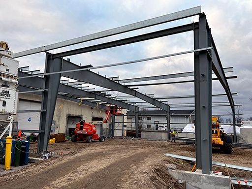 A large metal structure is being built in front of a building.