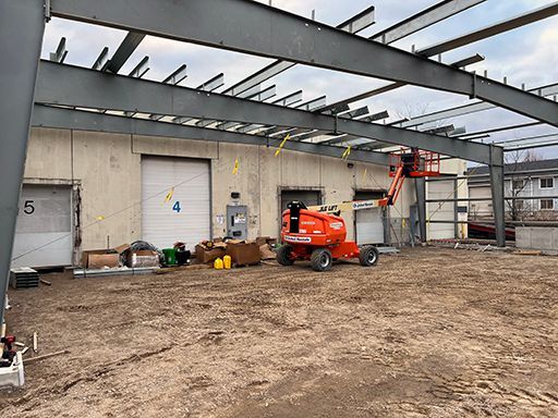 A large metal structure is being built on top of a dirt field.