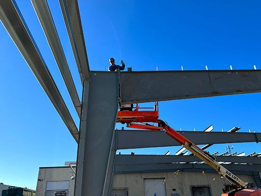 A man is standing on top of a metal structure on a lift.