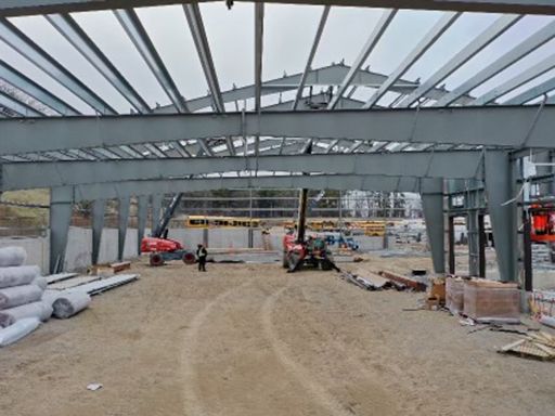 A large metal structure is being built on a dirt field.