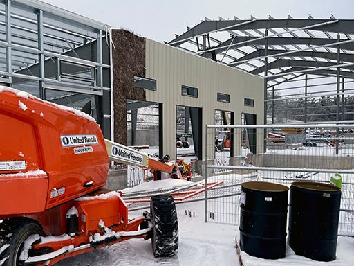 An orange construction vehicle is parked in front of a building under construction.