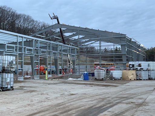 A large metal structure is being built in a parking lot.