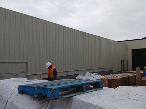 A man is standing next to a blue pallet in front of a building.