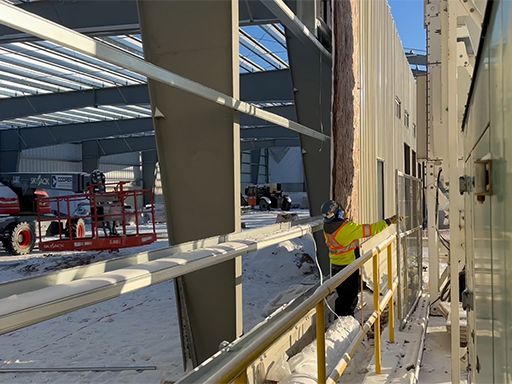 A construction worker is working on the side of a building.
