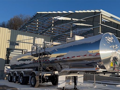 A large tanker truck is parked in front of a building under construction