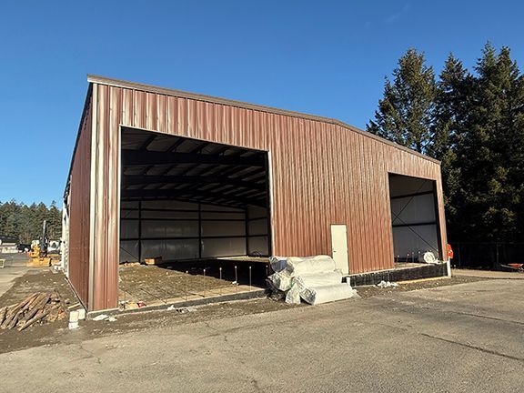 Brown metal building workshop photo with interior concrete floor waiting to be completed.