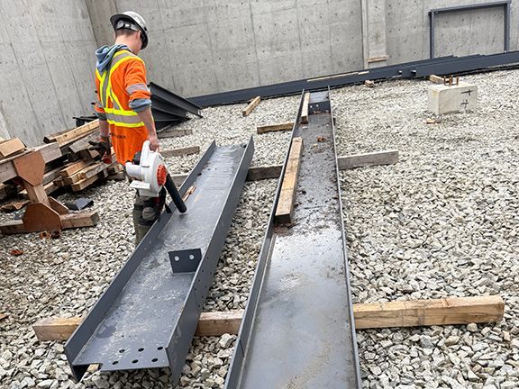 Skilled worker cleans steel beam before it gets installed at a building construction project.
